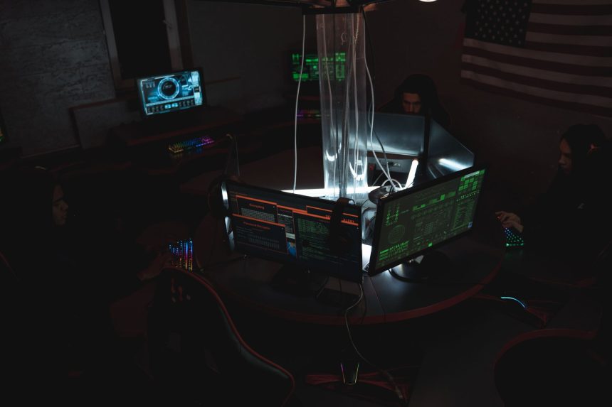 Equipe de profissionais de cibersegurança trabalha diante de computadores em uma sala com pouca iluminação