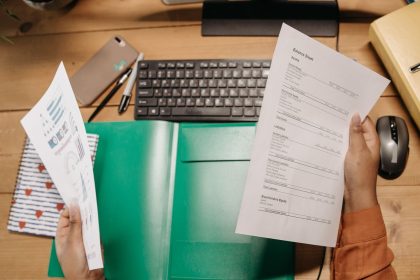 Mãos analisam planilhas financeiras sobre uma mesa com teclado e materiais de escritório.