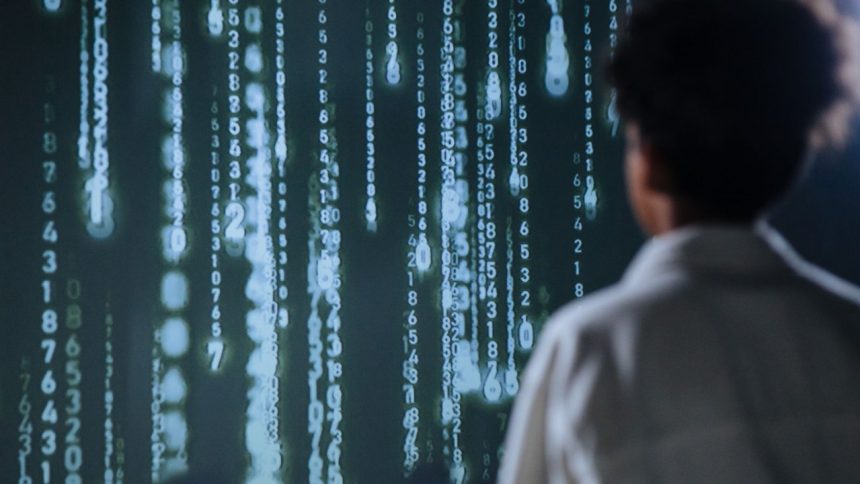 Pessoa observa números luminosos em uma tela, representando tecnologia e processamento de dados.